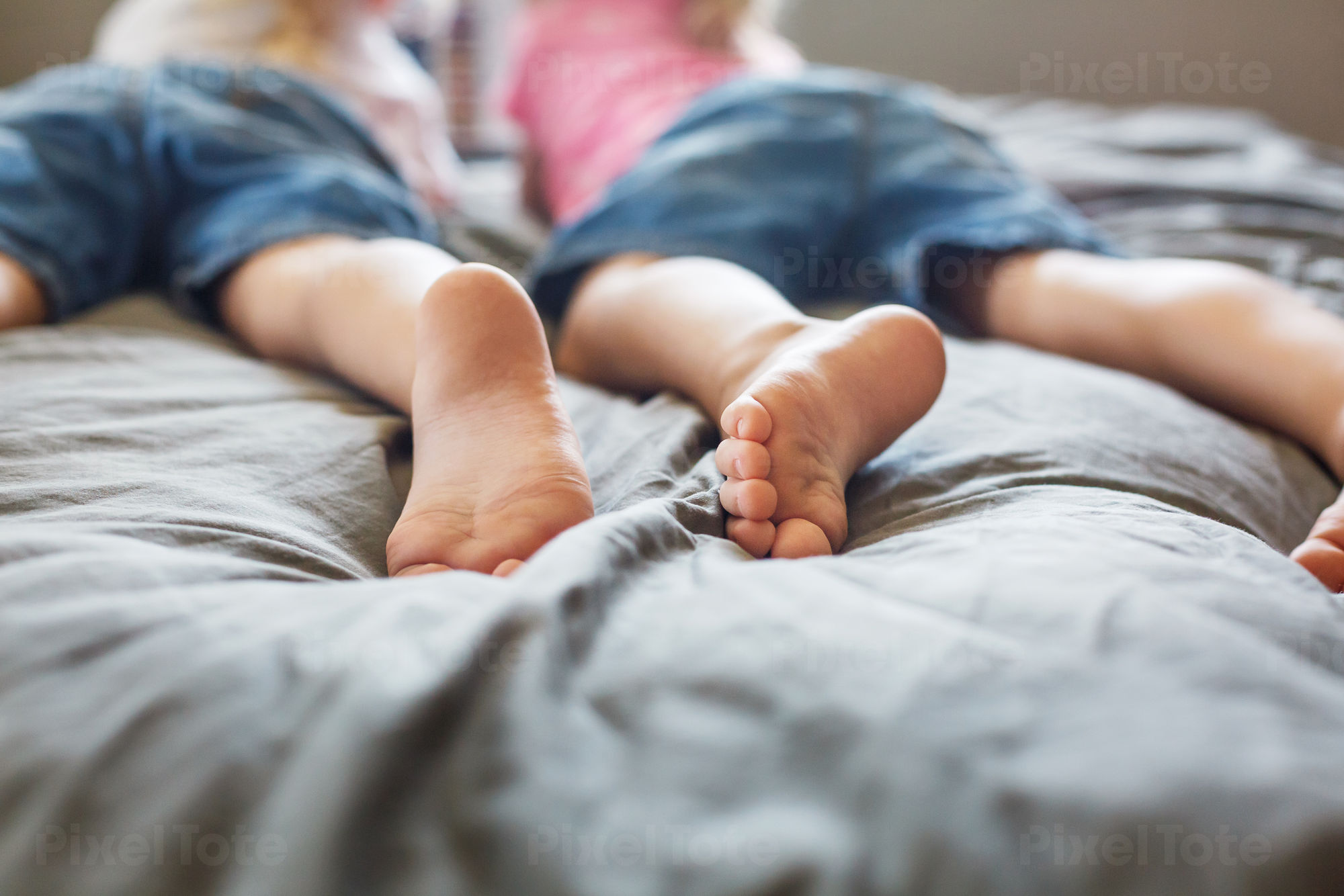 Child with bare feet in jeans. Lying on the bed. Foot barefoot Stock Photo