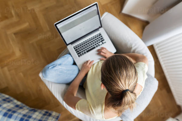 Overhead View of a Young Woman in Casual Clothing Working on a Laptop from Home