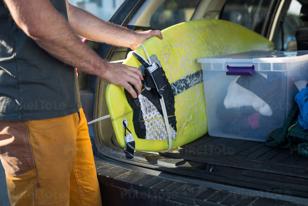 Surfer Loading a Surfboard into His Car