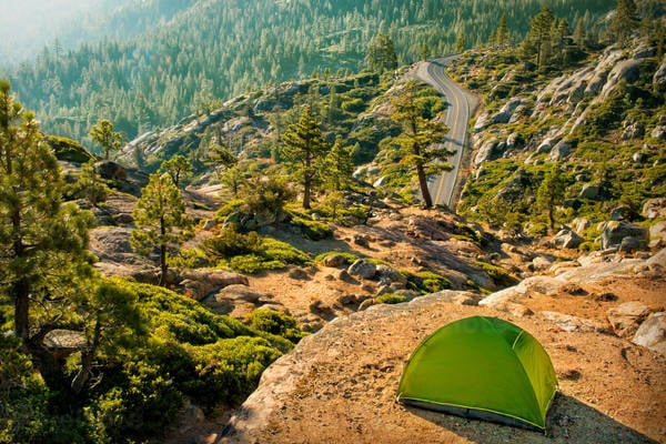 Tent Pitched on a Ledge with a Forest and a Road Below
