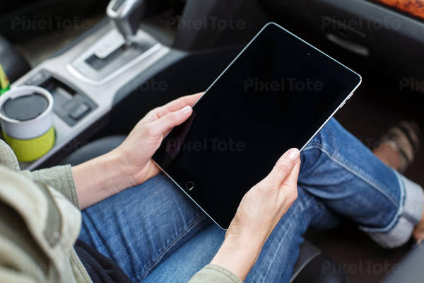 Woman Sitting in a Car Working on a Digital Tablet