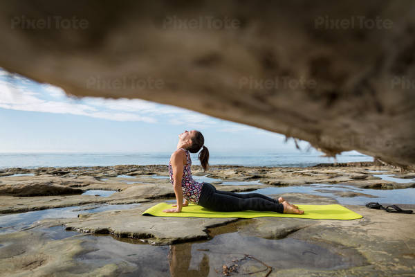 Focused Young Woman Practicing a Yoga Pose by the Ocean