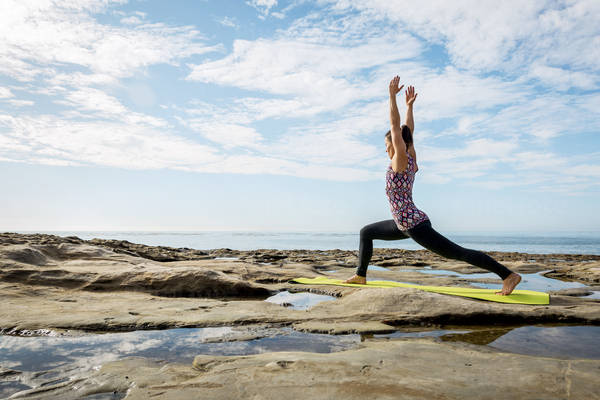Young Woman Practicing a Yoga Warrior Pose by the Ocean
