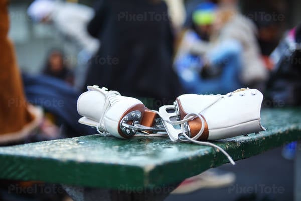 Close-Up of White Women's Ice Skates Laying on a Bench
