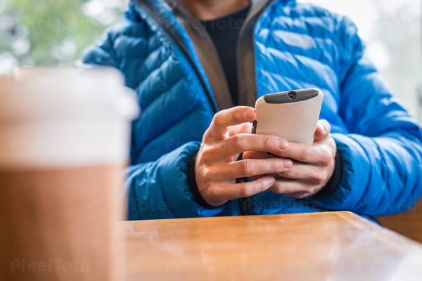 Table-Level Shot of a Man Looking at His Phone at a Coffee Place