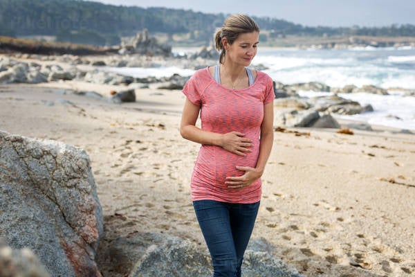 Pregnant Woman Stroking Her Belly While Walking on a Beach