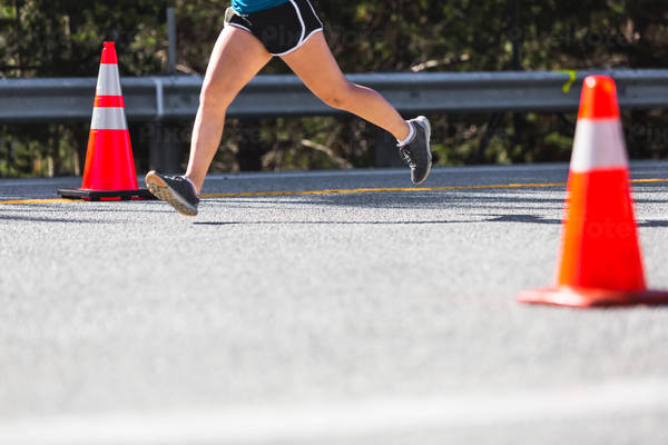 Lower Section of a Marathon Runner Running on a Road
