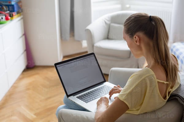 Young Woman in Casual Clothing Working on a Laptop from Home