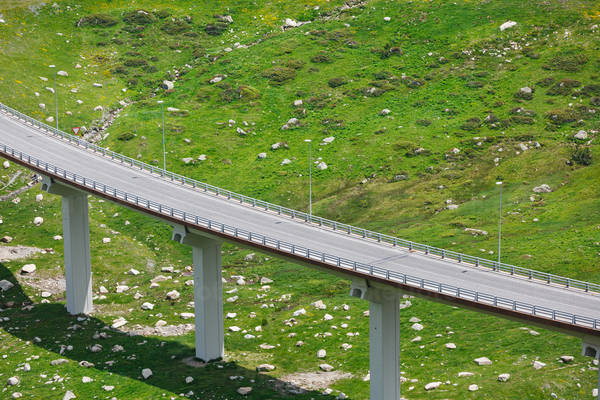 Road Overpass Above a Green Hillside with Dispersed Rocks