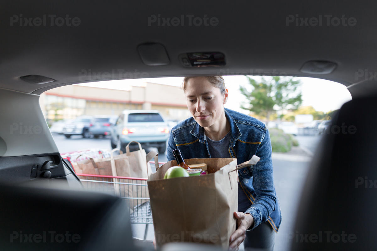 Woman Loading a Shopping Bag Stock Photo - PixelTote