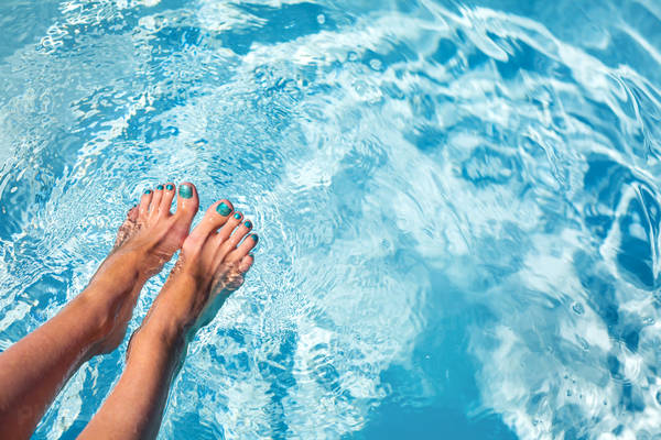 Close-Up of a Woman Dipping Her Feet in a Crystal Clear Water