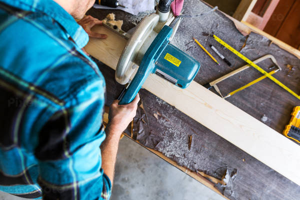 Overhead View of a Handyman Cutting a Wooden Board with a Miter Saw