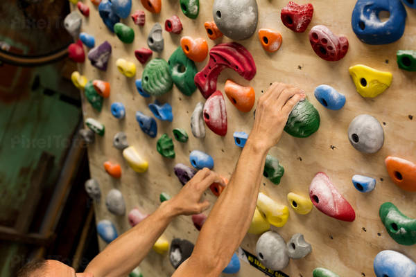 Man's Hands Gripping Holds on a Training Wall at Home