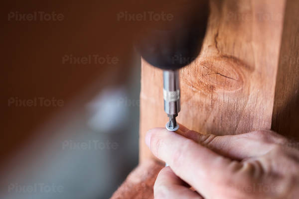 Close-Up of a Handyman Using an Electric Screwdriver in a Workshop