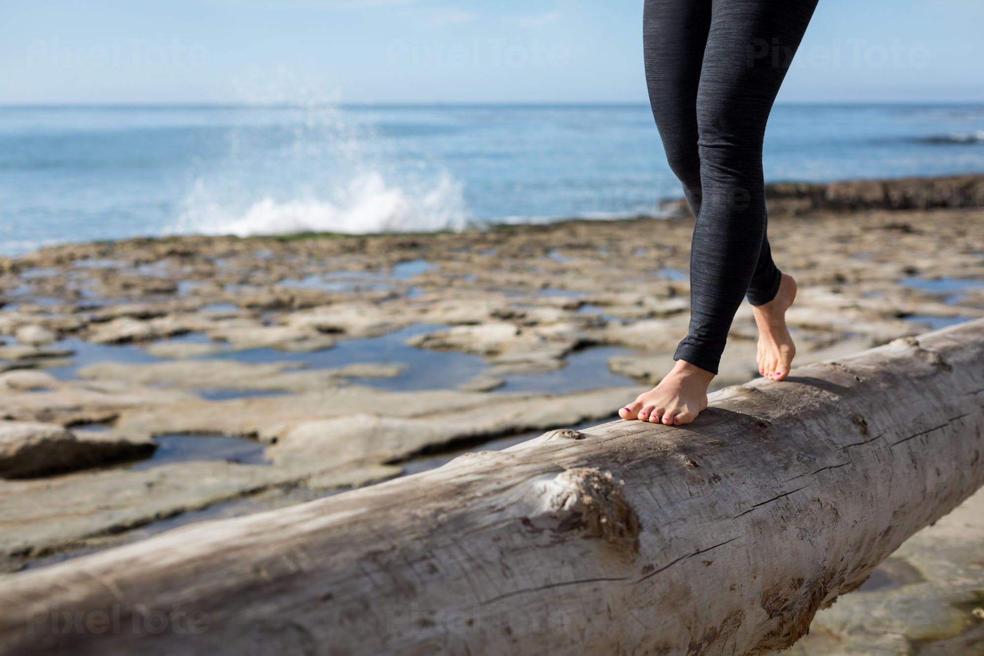 Young Woman in Flip Flops Walking on a Beach with a Yoga Mat