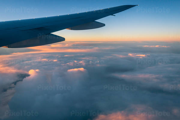 Airplane Wing with Clouds and Colorful Sky Seen Through a Window