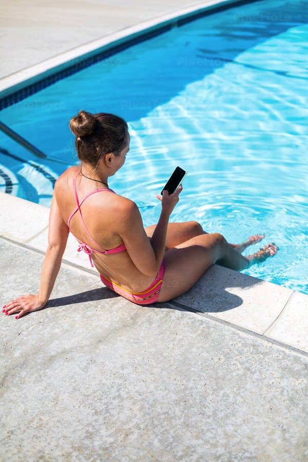 Woman in Bikini Sitting by Pool and Browsing on a Smartphone