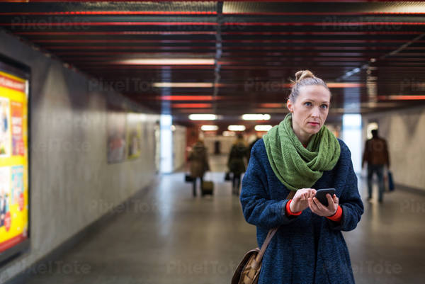 Woman Checking Her Phone in an Underpass During Morning Commute