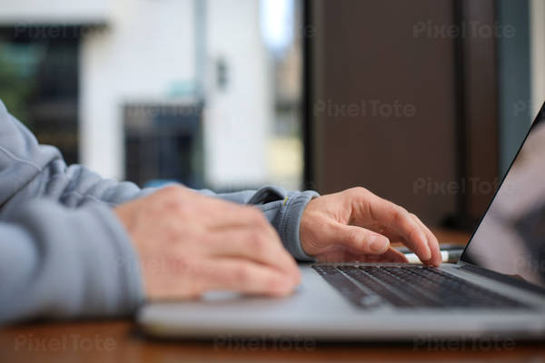 Low-Angle View of a Man Using a Laptop Inside a Coffee Shop
