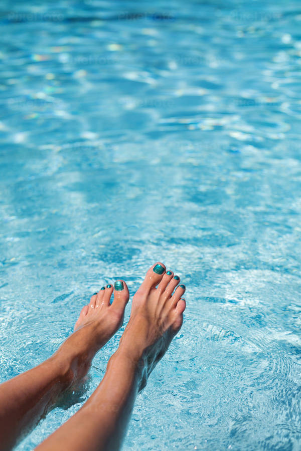 Close-Up View of a Woman Dipping Her Feet in a Turquoise Pool
