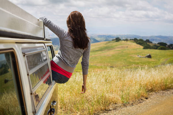 Girl Sitting in the Window a VW Bus Looking at Rolling Hills in the Distance