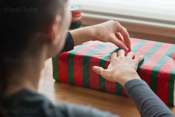 Woman Wrapping Christmas Present on a Table