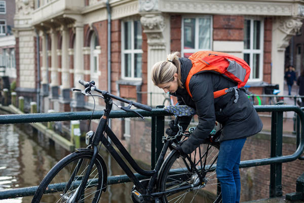 View of a Woman Locking Her Bicycle on a City Bridge