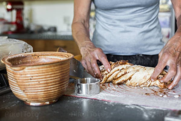 Senior Woman Shaping Cinnamon Bread Dough in a Kitchen