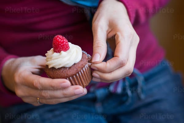 Woman Unwrapping a Cupcake She Is Holding in Her Hands