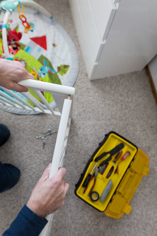 Overhead View of a Man Assembling a Baby Crib in a Children's Room