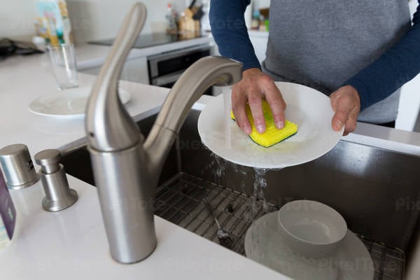 Man Washing Dishes in a Sink at a Modern Home