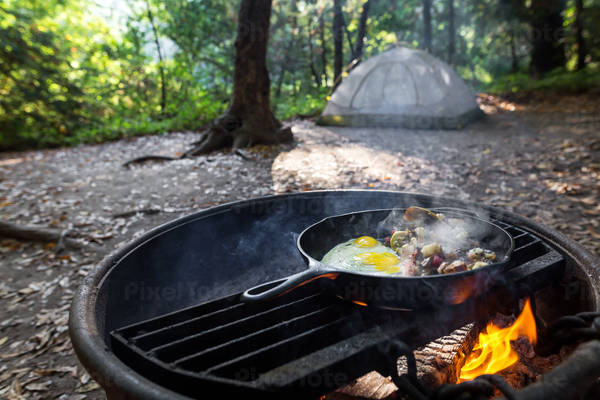 An Iron Skillet with Breakfast Eggs and Potatoes on a Fire Pit