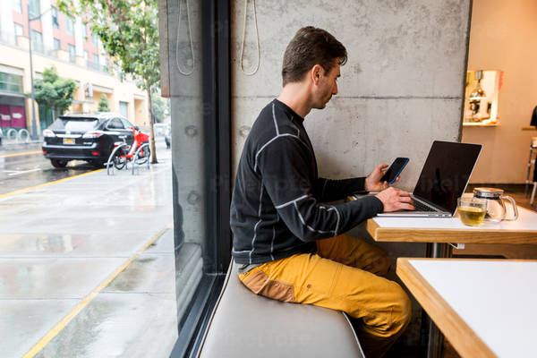 Web Developer Working from a Cafe and Using a Cell Phone