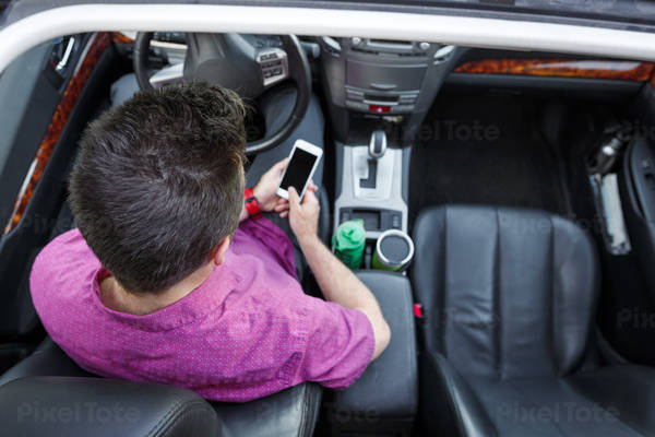 Overhead View of a Car Interior with a Man Using a Cell Phone