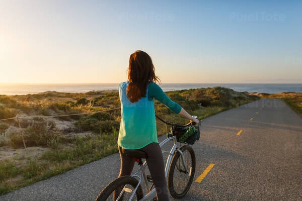 Woman on a Cruiser Bike on a Bike Path Watching Sunset