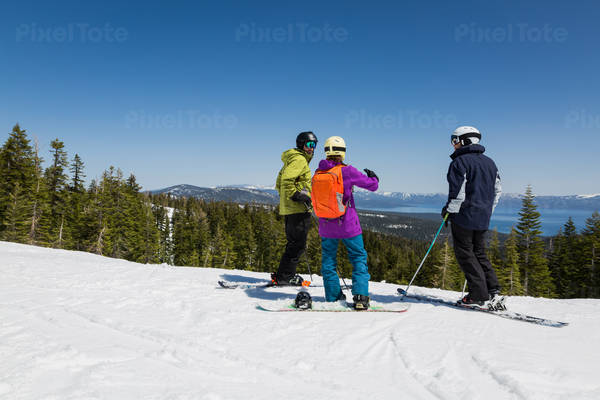 Skiers and a Snowboarder at a Sunny Scenic Mountain Ski Resort