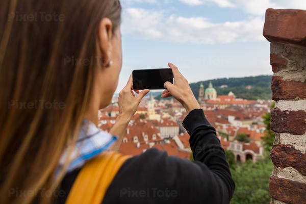 Female Traveler Taking a Picture of a Historic Town with Her Smartphone