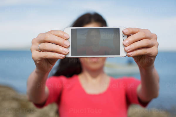 Young Woman Holding a Phone in Her Hands While Taking a Self Portrait