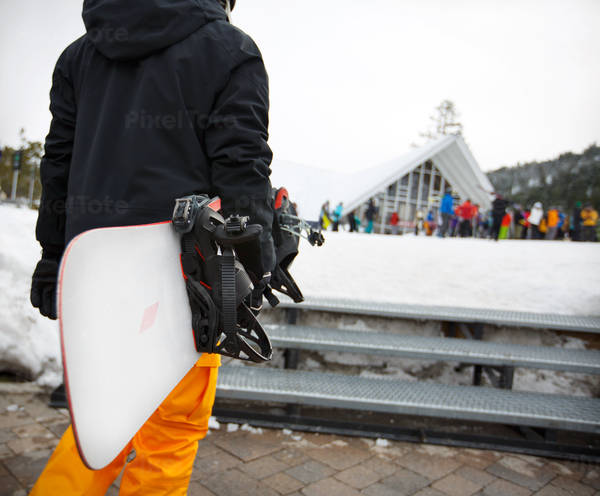 Man Carrying a Snowboard at a Ski Resort