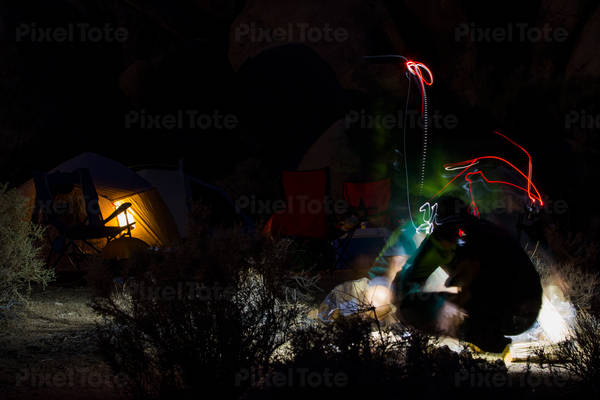 Night Shot of a Hiker at a Camp with Multiple Light Trails from the Headlamp