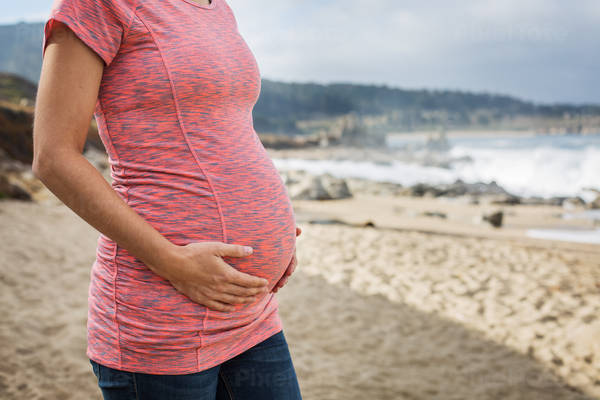 Pregnant Woman Standing on a Beach and Holding Her Belly