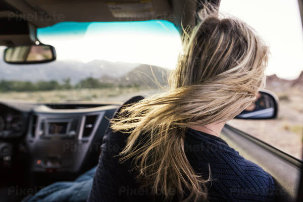 Rear View of a Woman in a Car with Her Blonde Hair Blowing in Wind