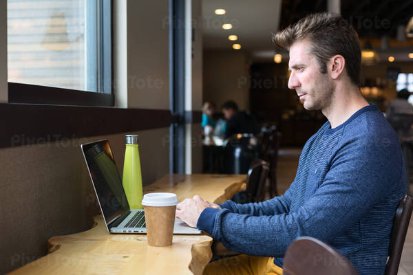 Man Working Remotely on a Laptop from a Coffee Shop