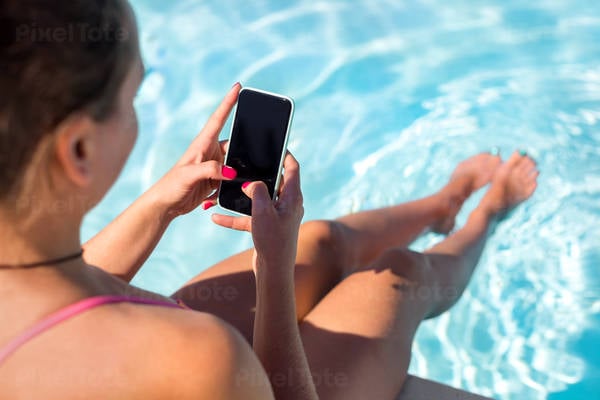 Close-Up View of a Woman Siting by Pool and Typing on a Smartphone