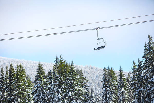 View of an Empty Ski Chair Going down with Snow Covered Trees Behind