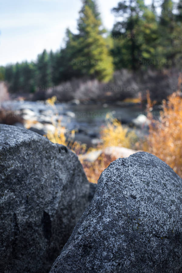 Close-Up View of Two Granite Boulders with a River in the Background