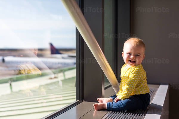 Smiling Baby Girl Sitting by a Window at the Airport