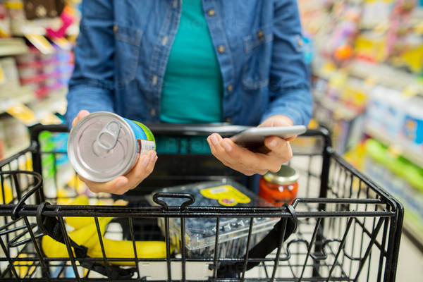 Close-Up of Woman Researching Information on a Cell Phone While Grocery Shopping
