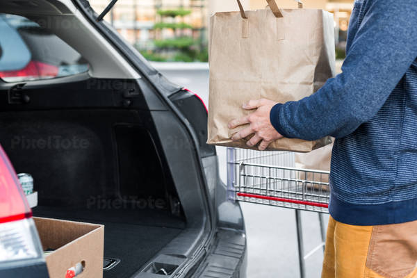 Man Loading a Bag with Groceries in a Hatchback Car