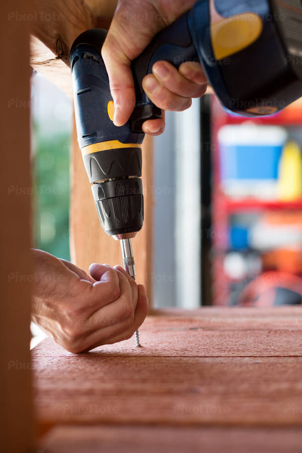 Close-Up of a Handyman Using an Electric Screwdriver in his Workshop